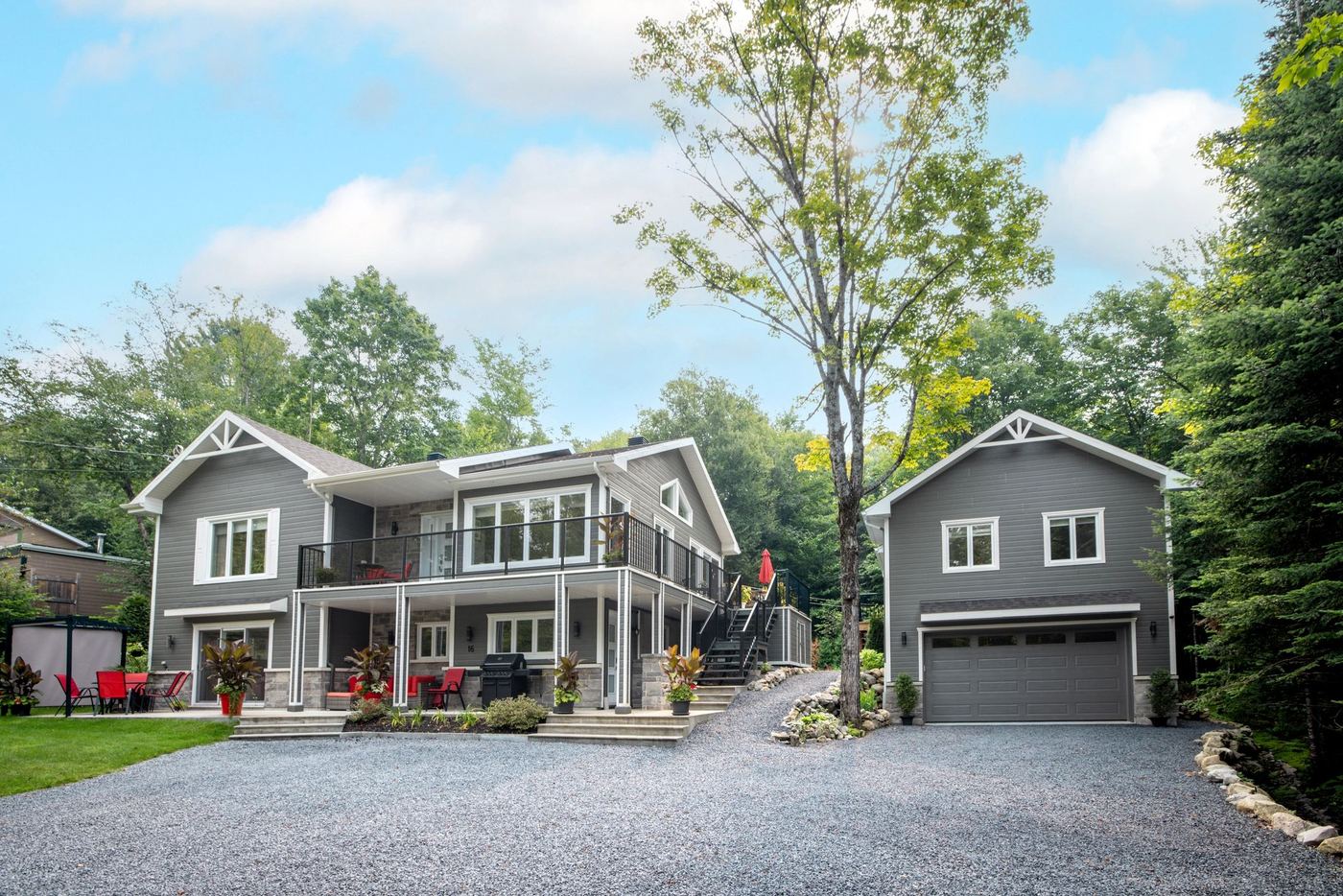 A newly finished two-storey home with a covered porch, detached garage, and fresh gravel driveway.